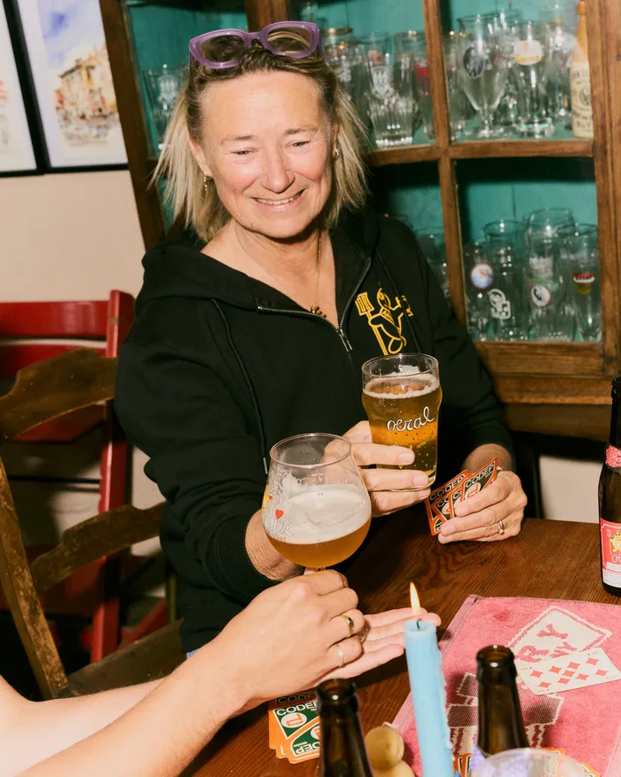 Een vrouw die lachend haar glas heft in de Oerbar